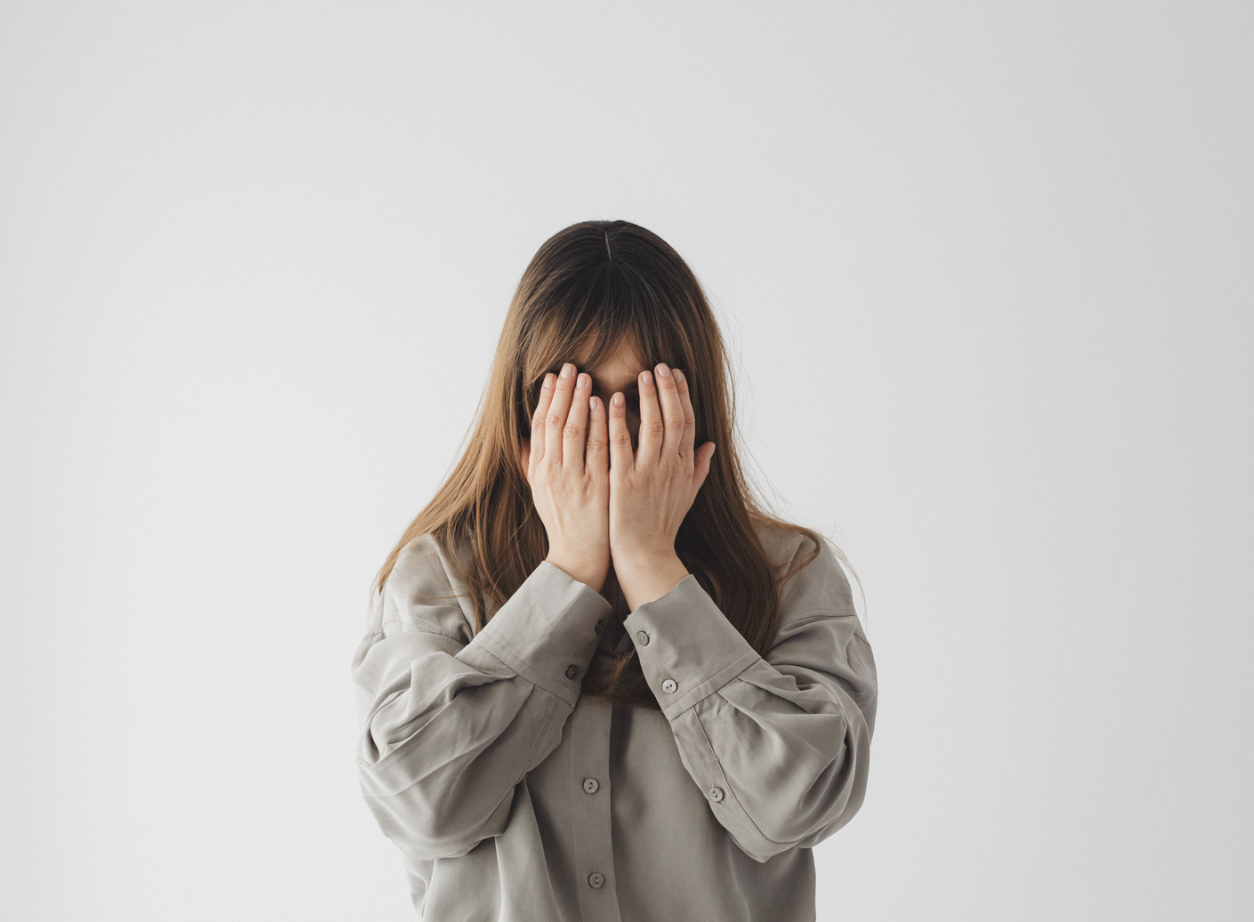 Woman covering her face feeling not ready for yoga teacher training